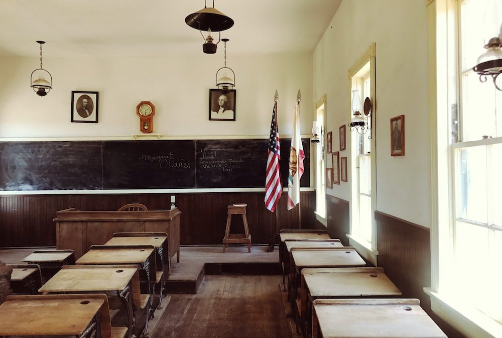An Outdated Classroom with a Chalkboard, Hanging Lights, and Old Furniture